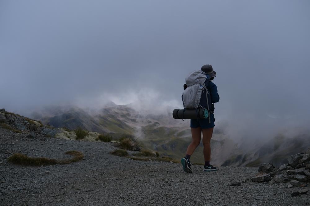 Mizuki stands amidst swirling grey clouds looking out from the ridgeline of Mt Roberts