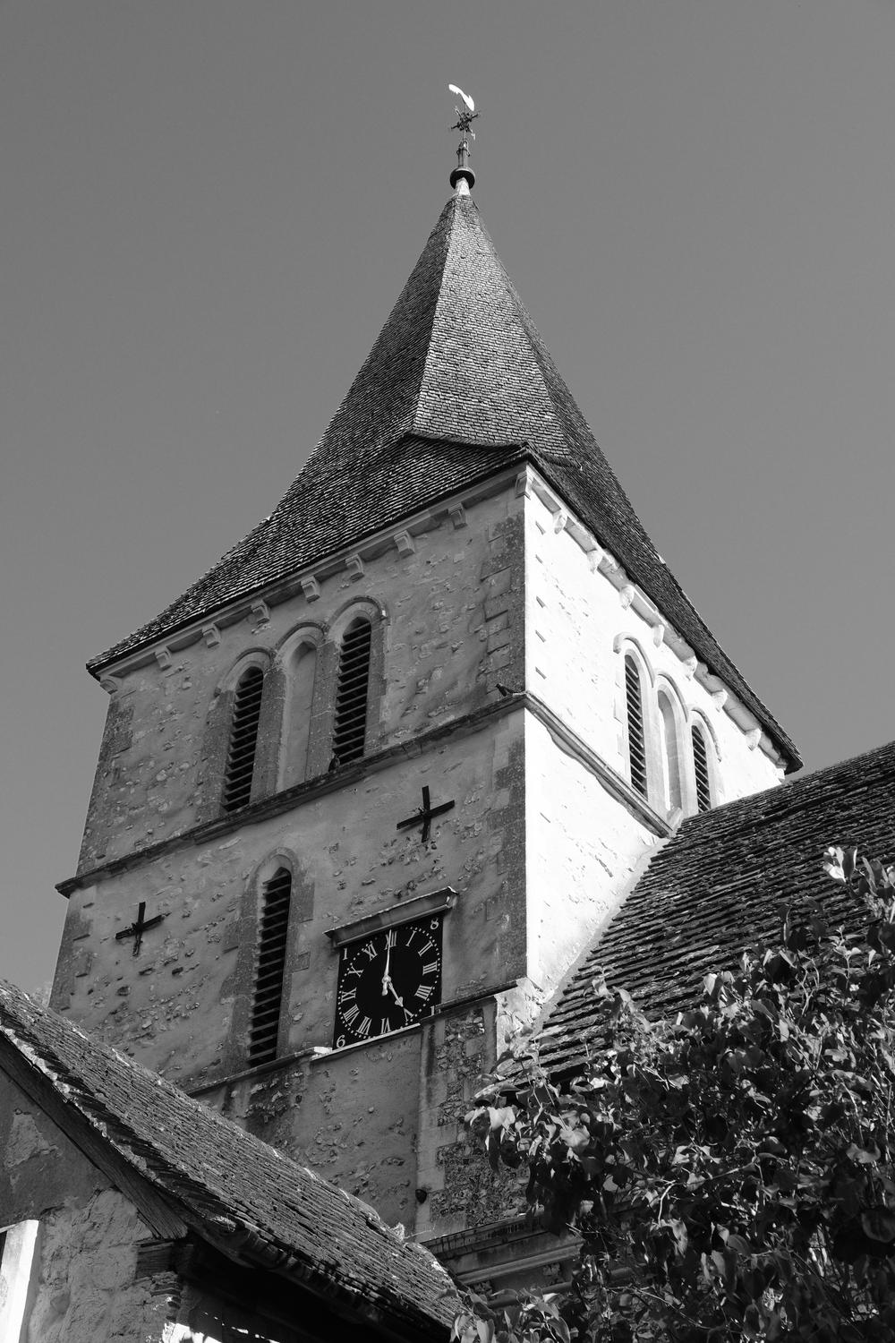 Looking up at the clock and spire of a church
