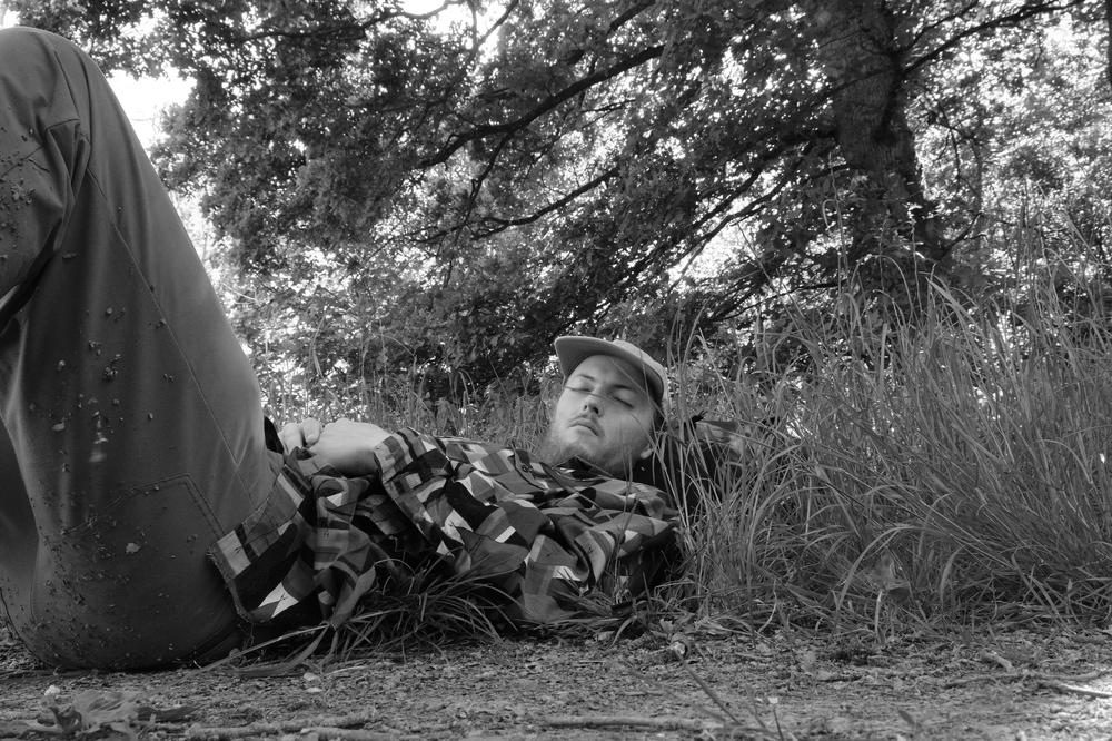 Me, feigning sleep at the edge of a field