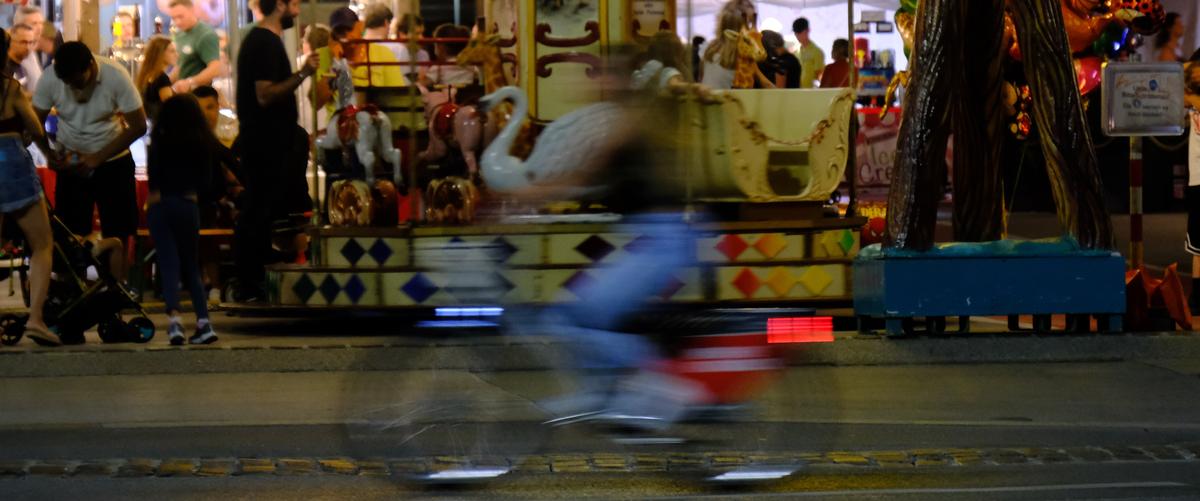 A crop of a motion blurred cyclist in front of a merry go round. Innsbruck, Austria 